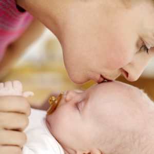 Woman Kissing the Top of a Baby's Head (3-6 Months) --- Image by © Royalty-Free/Corbis